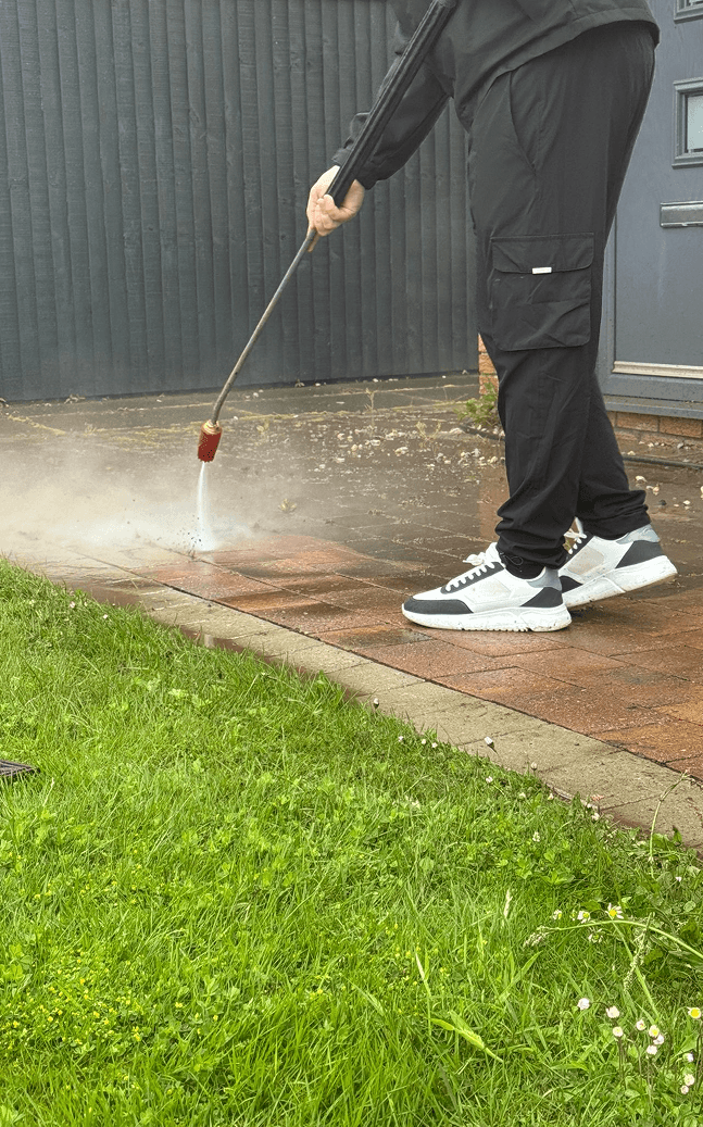 One of the staff members of smart care pressure washing power washing a small red concrete area