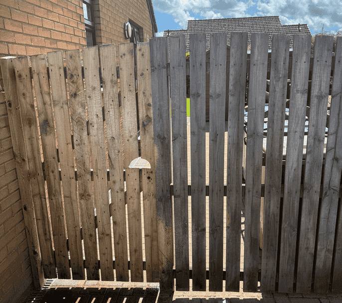 Stock image of wooden fence in the middle of being power washed